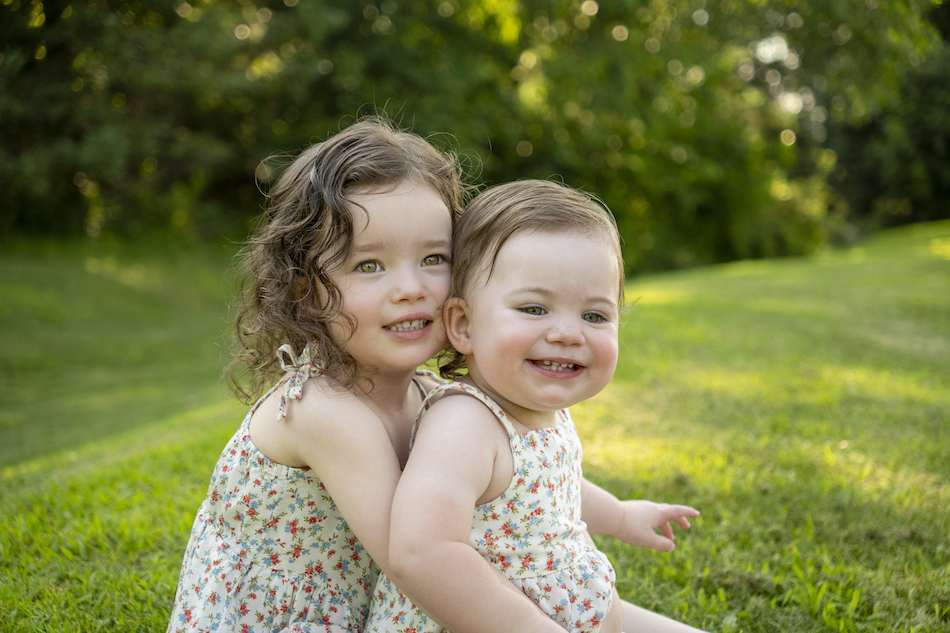 Two young sisters sitting together outdoors