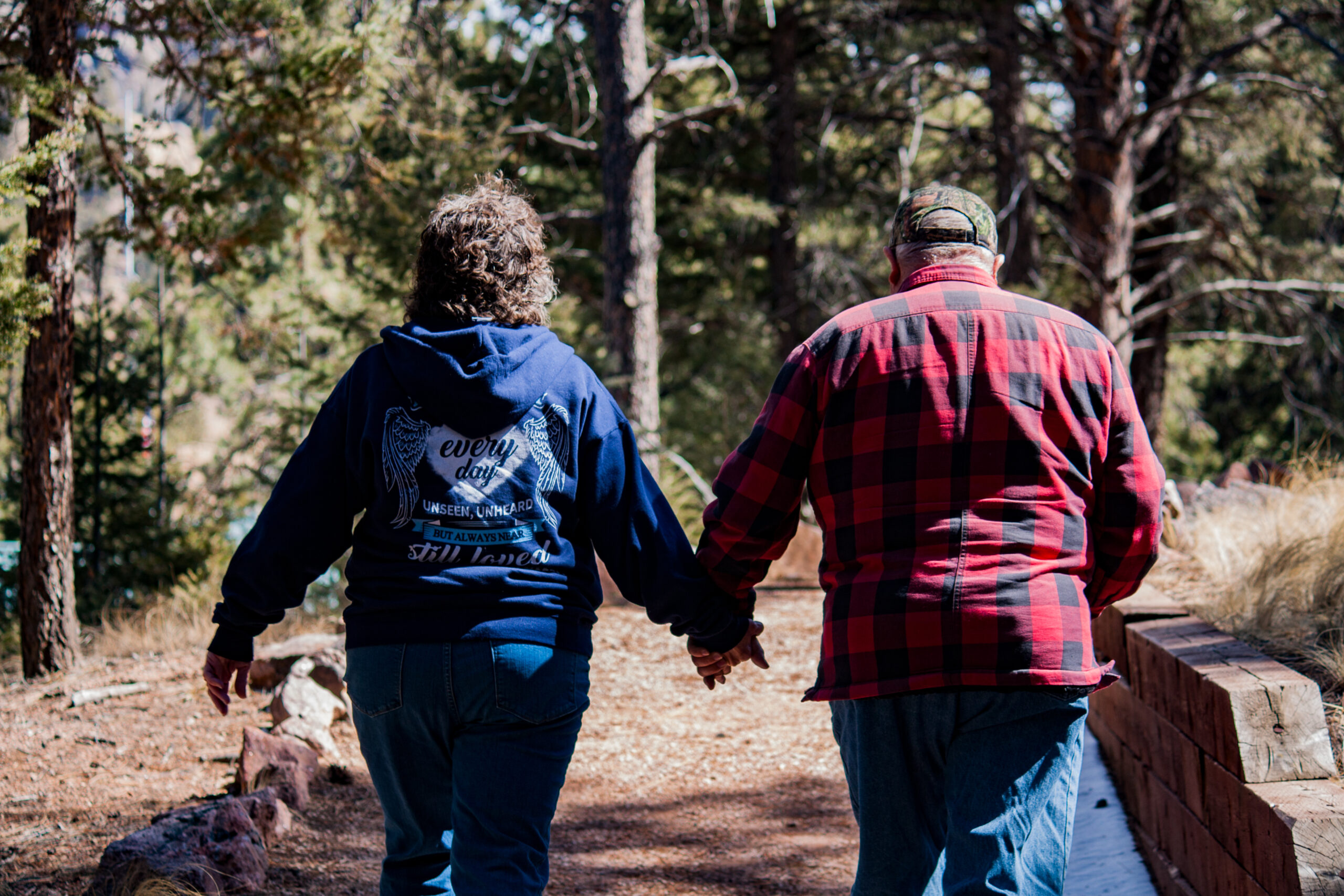 A couple holding hands while walking along a wooded trail