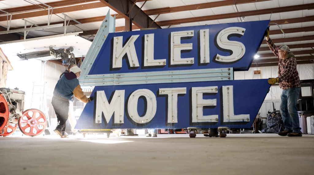 Large neon sign being moved on hand carts